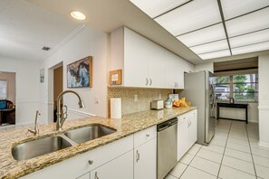 Una cocina moderna con encimeras de granito, electrodomésticos de acero inoxidable y armarios blancos.