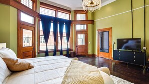 Ein Schlafzimmer mit einem großen Bett, Holzböden, einem Fernseher und Blick ins Freie durch große Fenster.