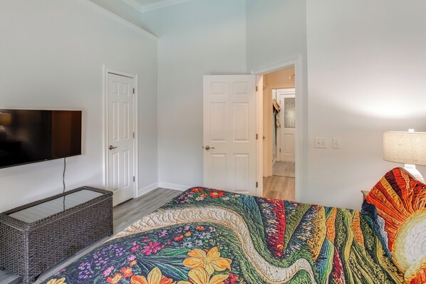 A bedroom with a bed, a television, a door, and a lamp.