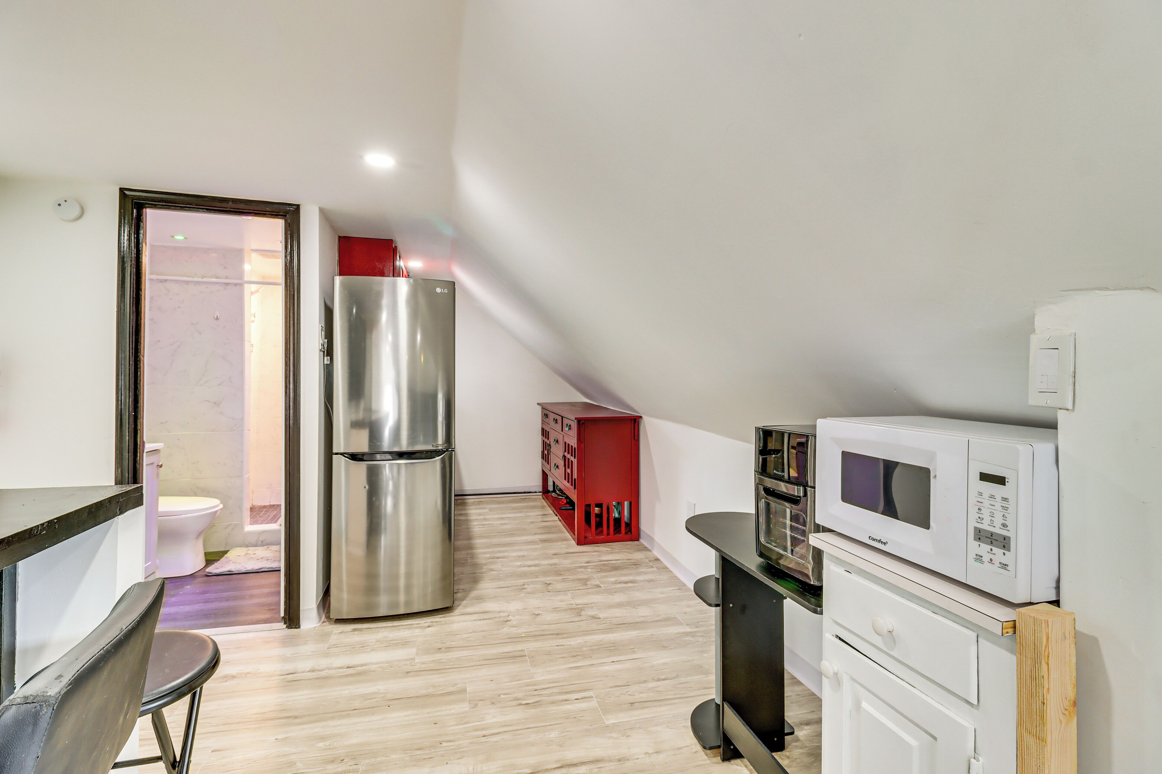 A compact kitchen with a refrigerator, microwave, and a small dining area.