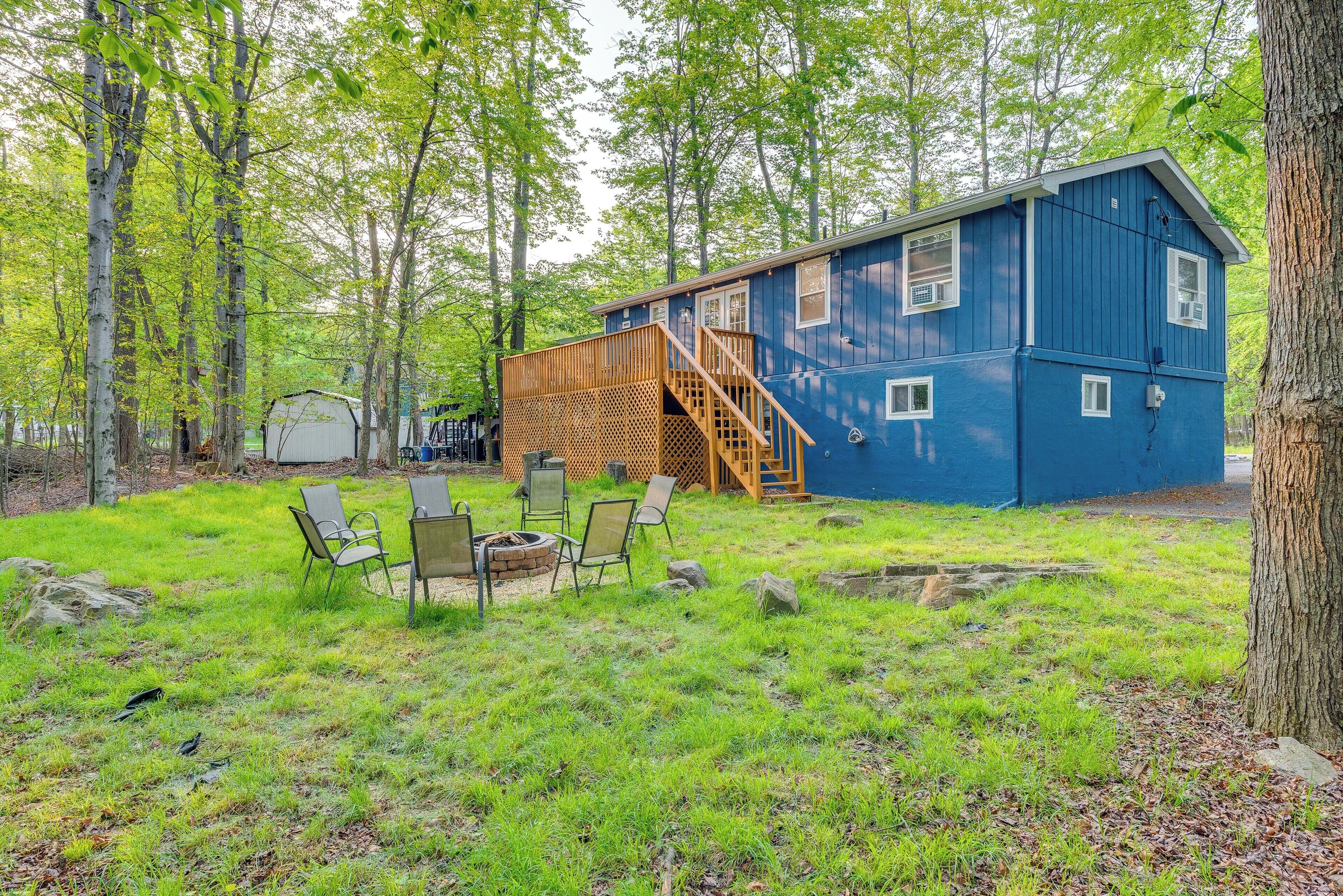 A blue cabin with a wooden deck and outdoor seating area.