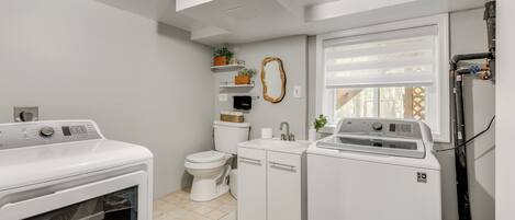 A compact laundry room with a washing machine, dryer, and a toilet.