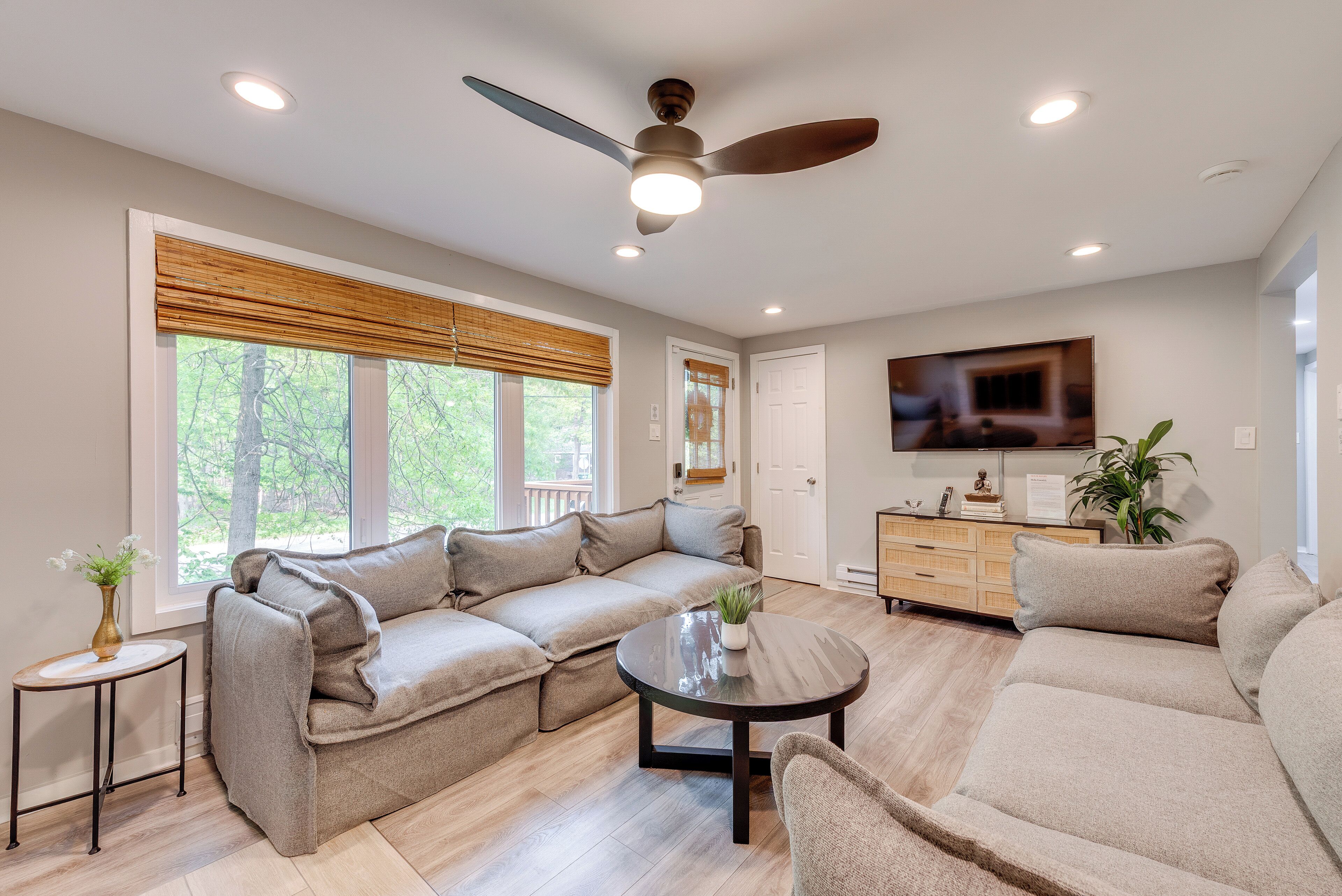 A modern living room with a sectional sofa, a round coffee table, and a ceiling fan.
