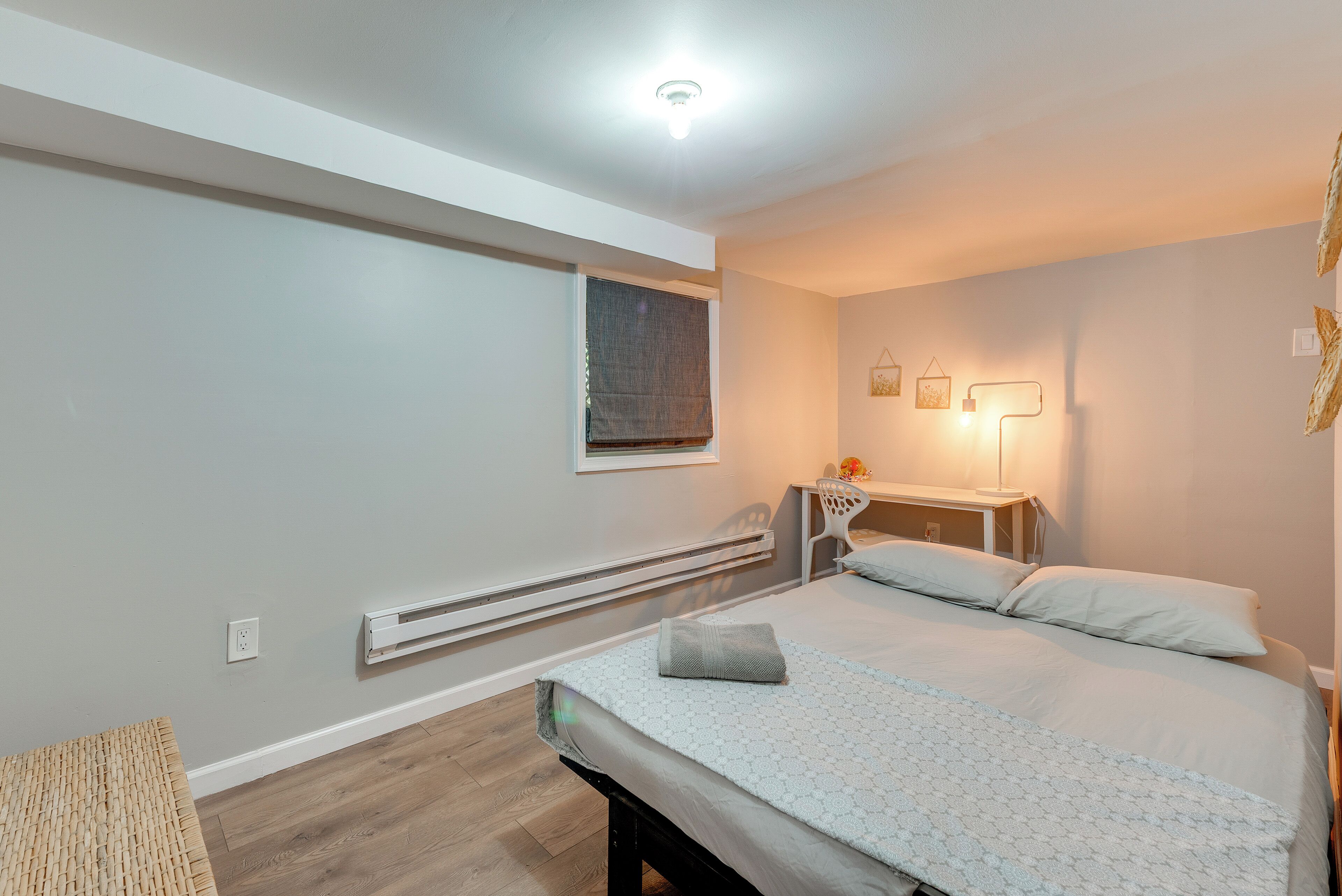 A bedroom with a bed, bedside table, lamp, and a window with a blind.