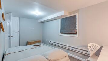 Une chambre à coucher avec un lit, une chaise, une fenêtre, un radiateur et une porte.