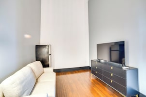 Una sala de estar moderna con un sofá, un mueble de entretenimiento negro y un televisor de pantalla plana.