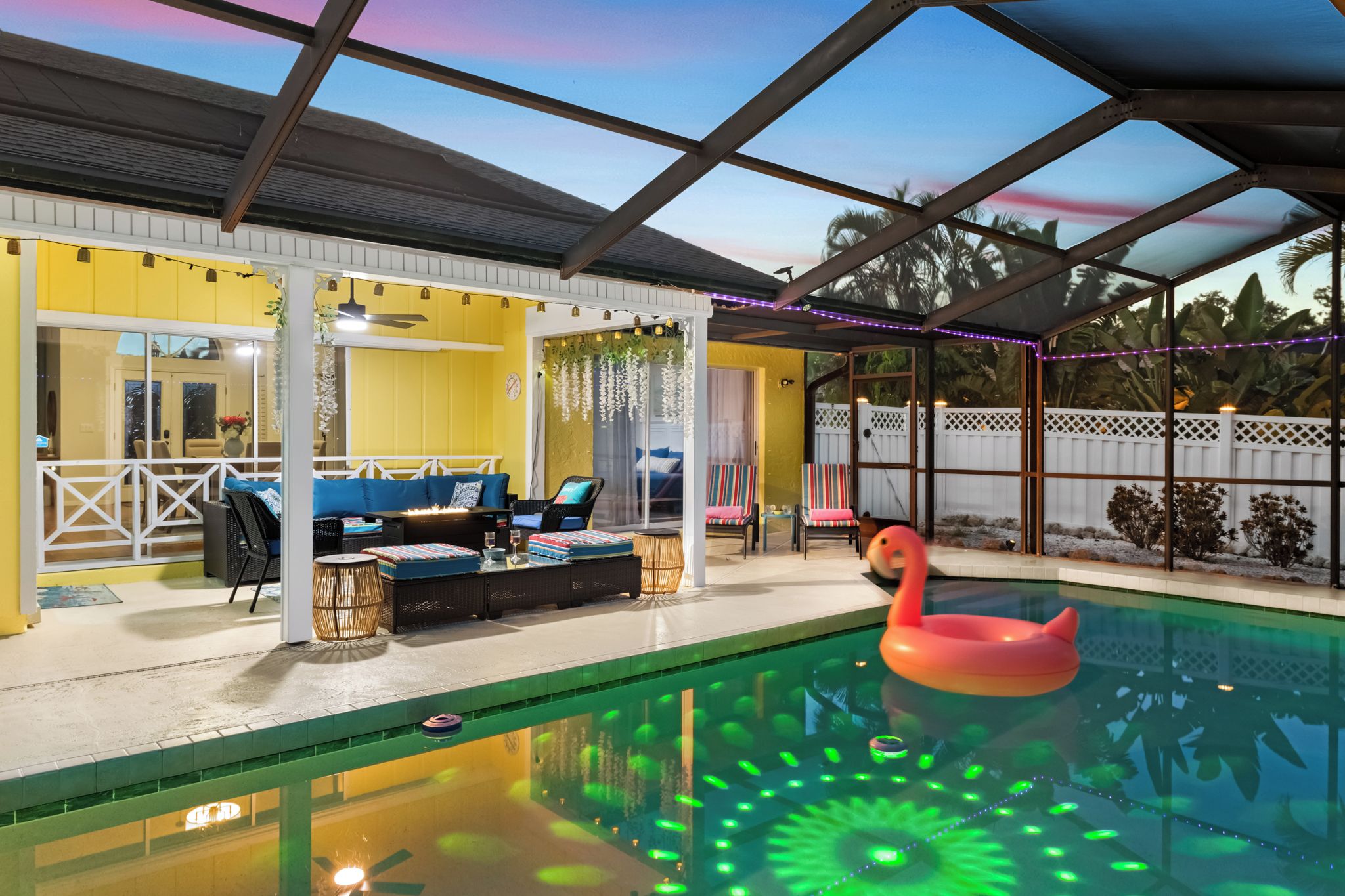 Una piscina interior con un flotador de flamenco, rodeada de zonas de estar y un patio cubierto.