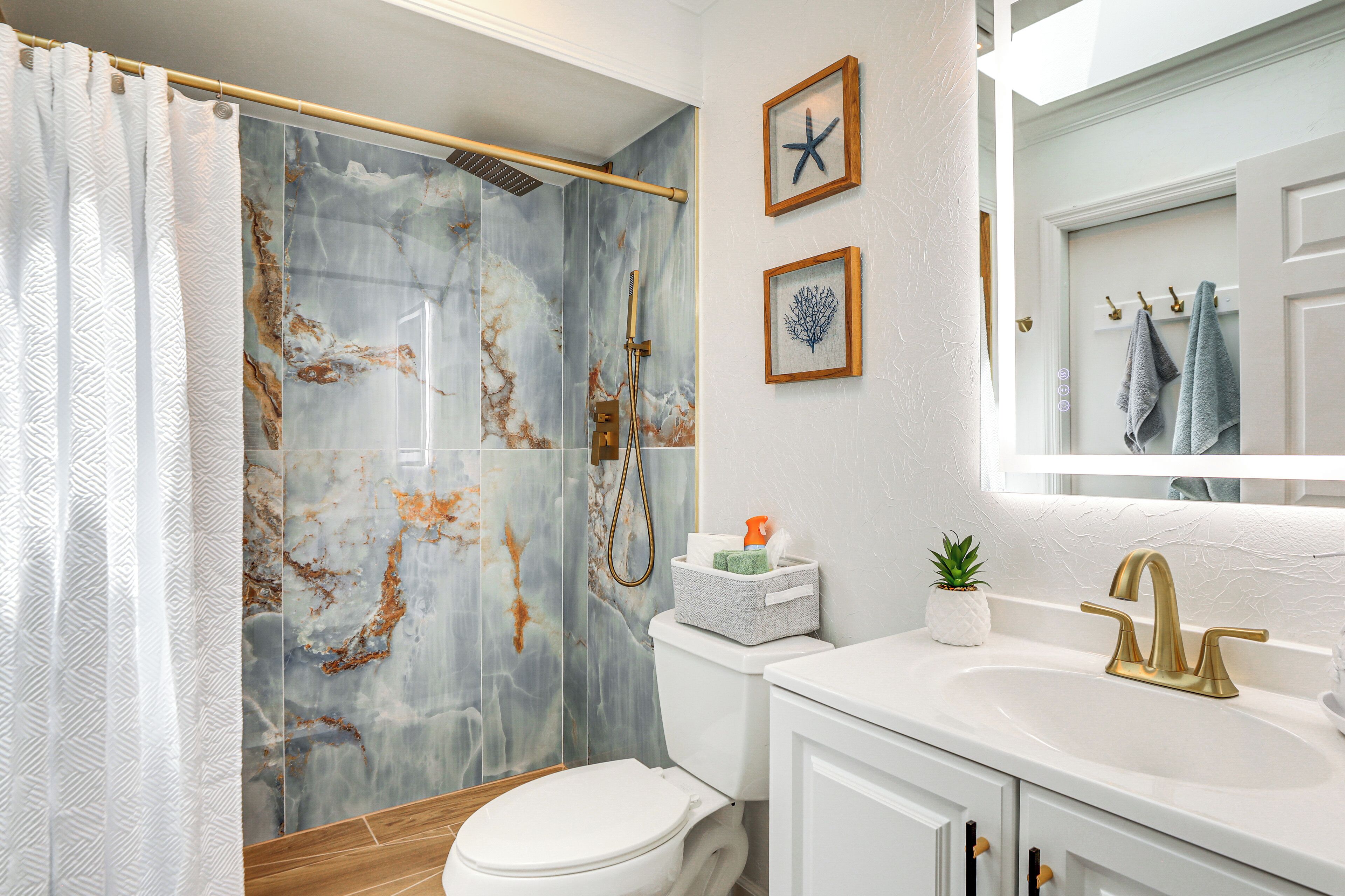 A bathroom with a shower, toilet, sink, and a mirror.