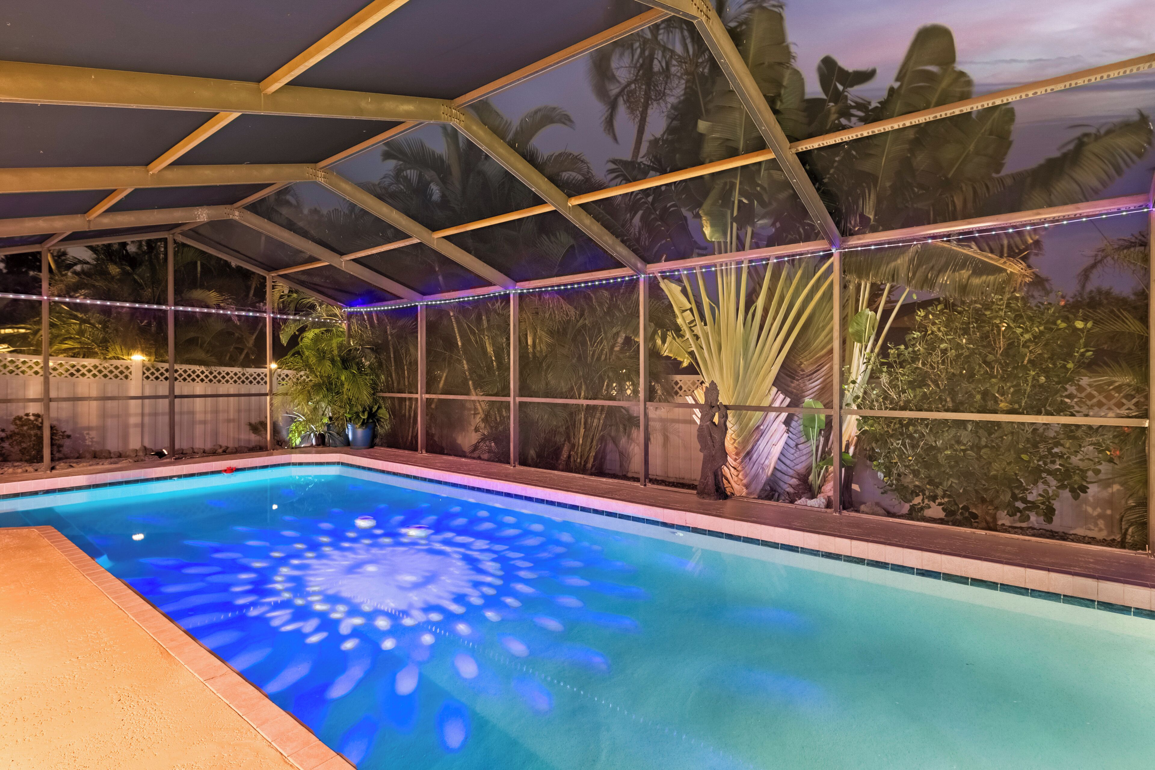 An indoor swimming pool with a glass ceiling and tropical plants.