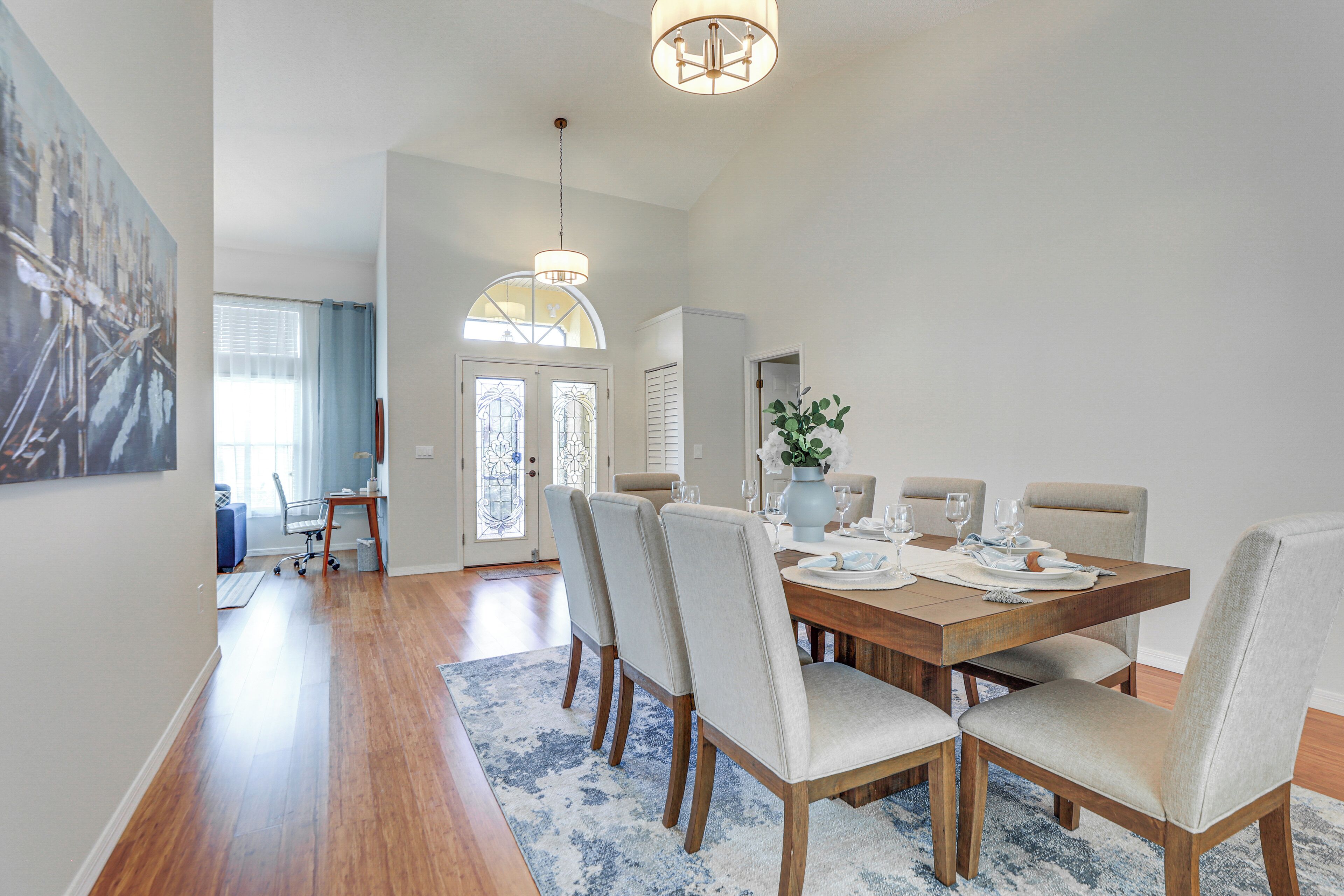 A dining area with a wooden table set for four, surrounded by upholstered chairs.