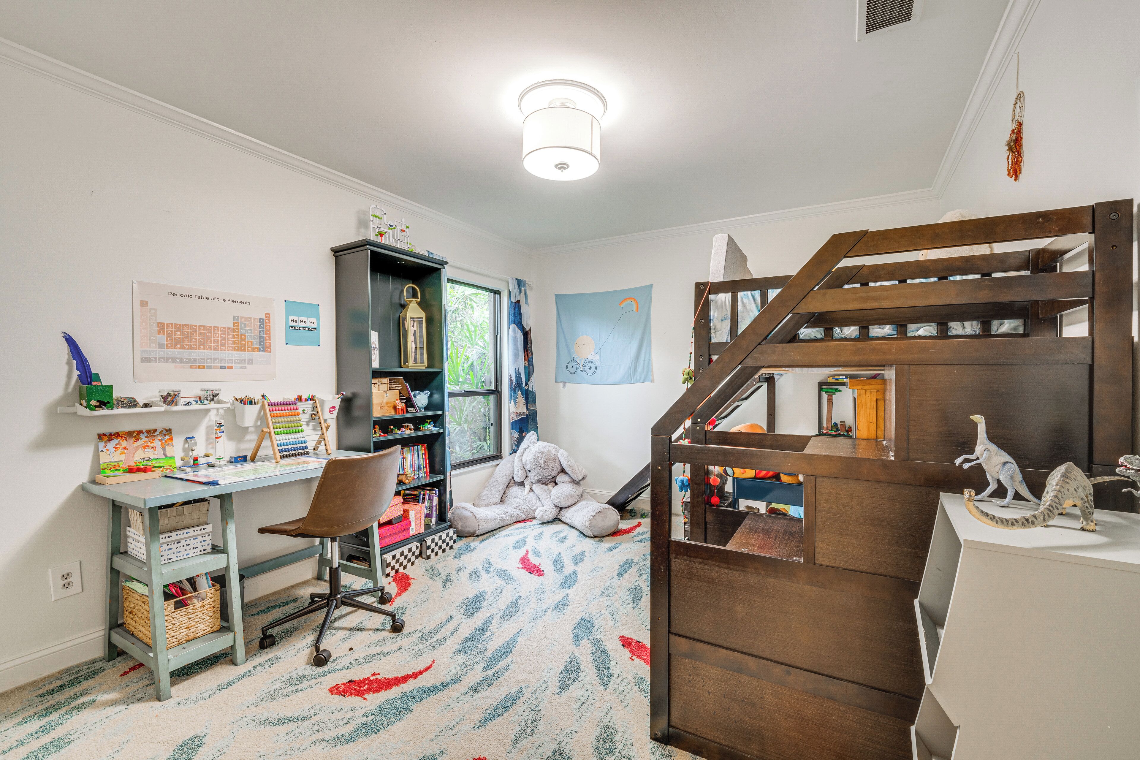 Habitación infantil con escritorio, silla, estantería y zona de juegos con un tobogán.