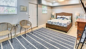 A bedroom with a bed, two wicker chairs, a small table, a rug, and a desk. - Apt 3 Mi to Beach & Daytona Boardwalk Amusements! (Holly Hill)