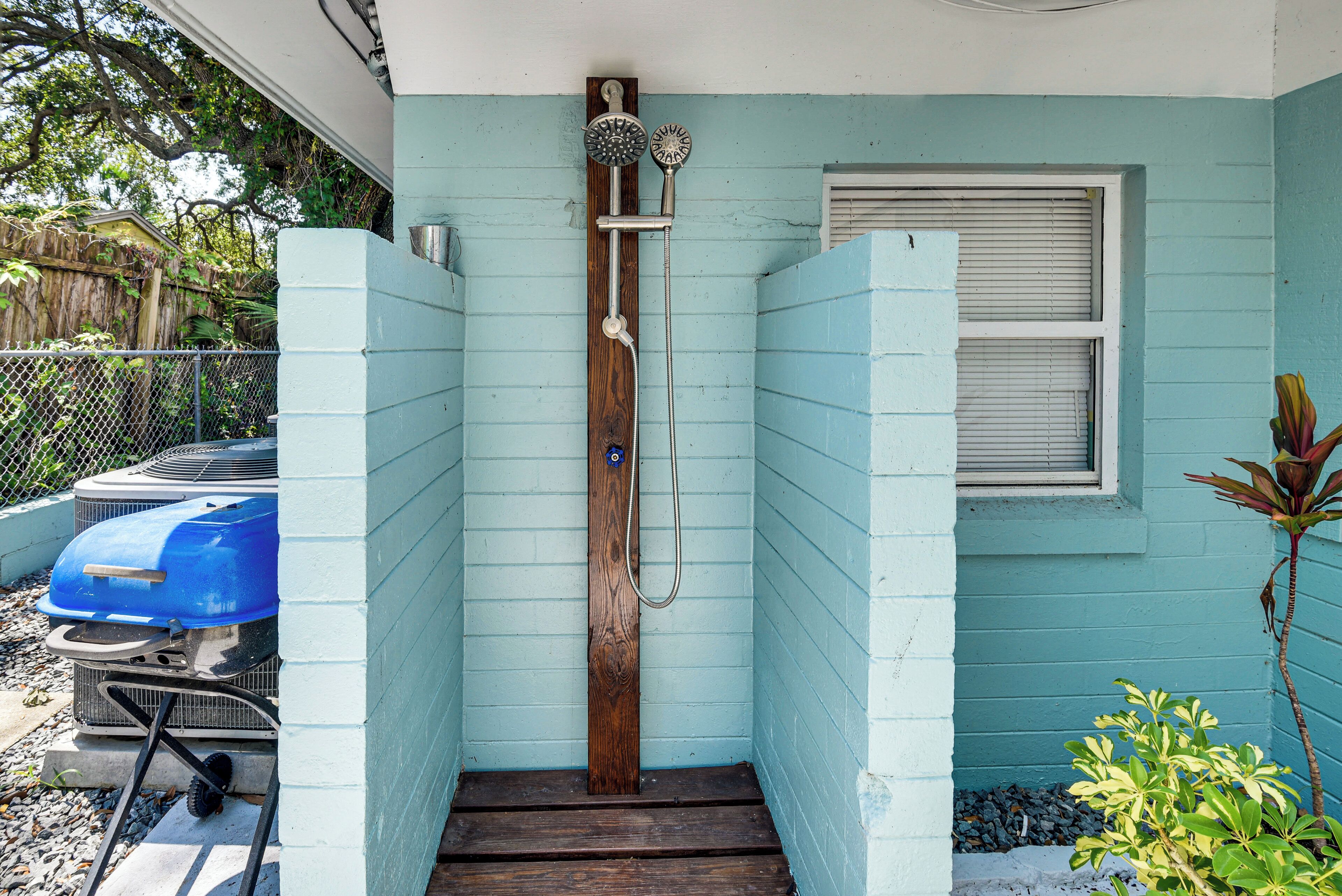 A narrow wooden staircase leading to a door with a showerhead mounted on a wooden post.