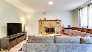A living room with a fireplace, a sofa, a TV, and a wooden cabinet.