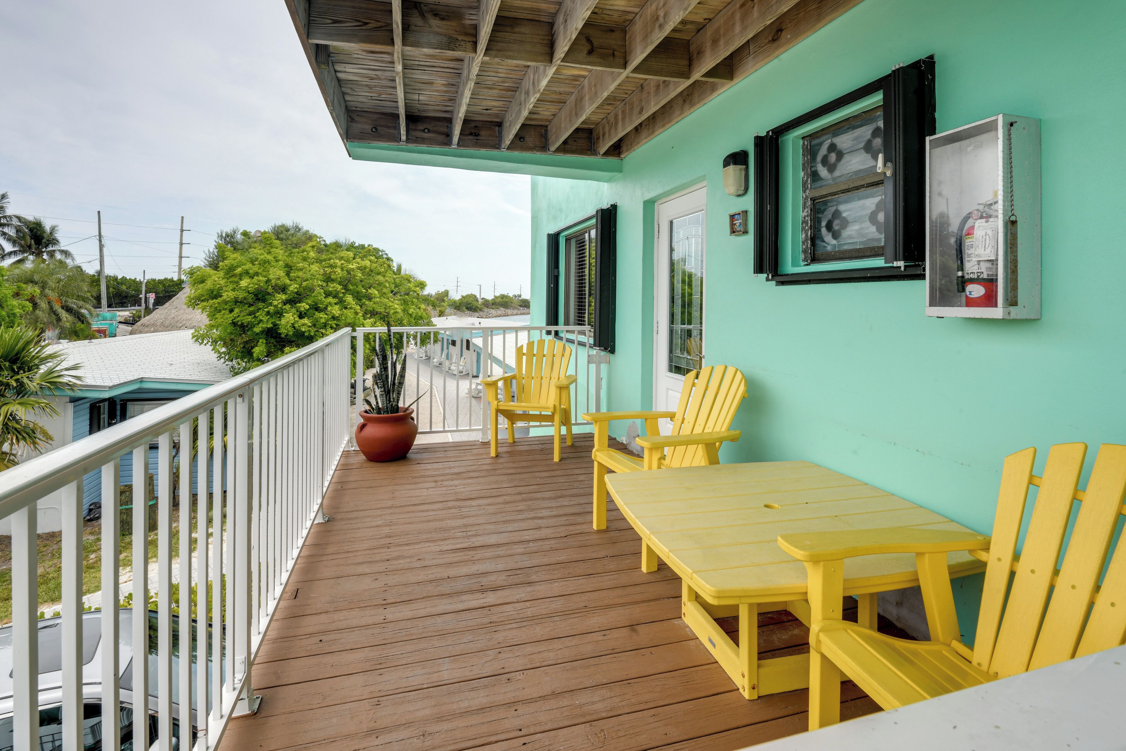 A covered outdoor area with a wooden deck, yellow chairs, and a table.