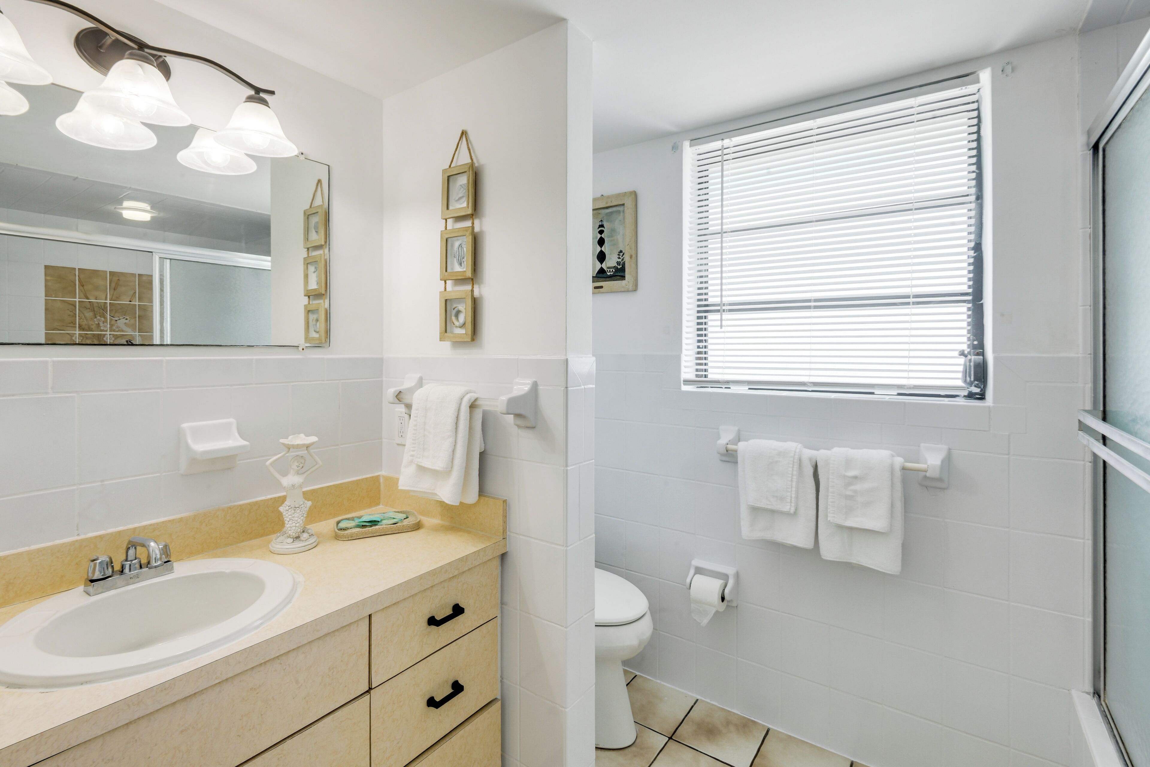 A bathroom with a sink, vanity, mirror, and toilet.
