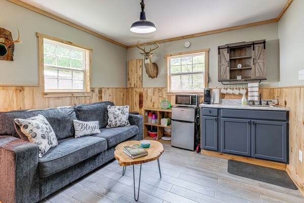 A cozy living room with a grey sofa, a wooden coffee table, and a mounted deer head.