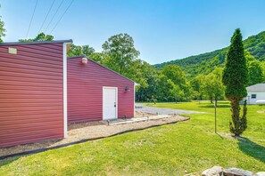 A red building with a white door, surrounded by a well-maintained lawn and trees.