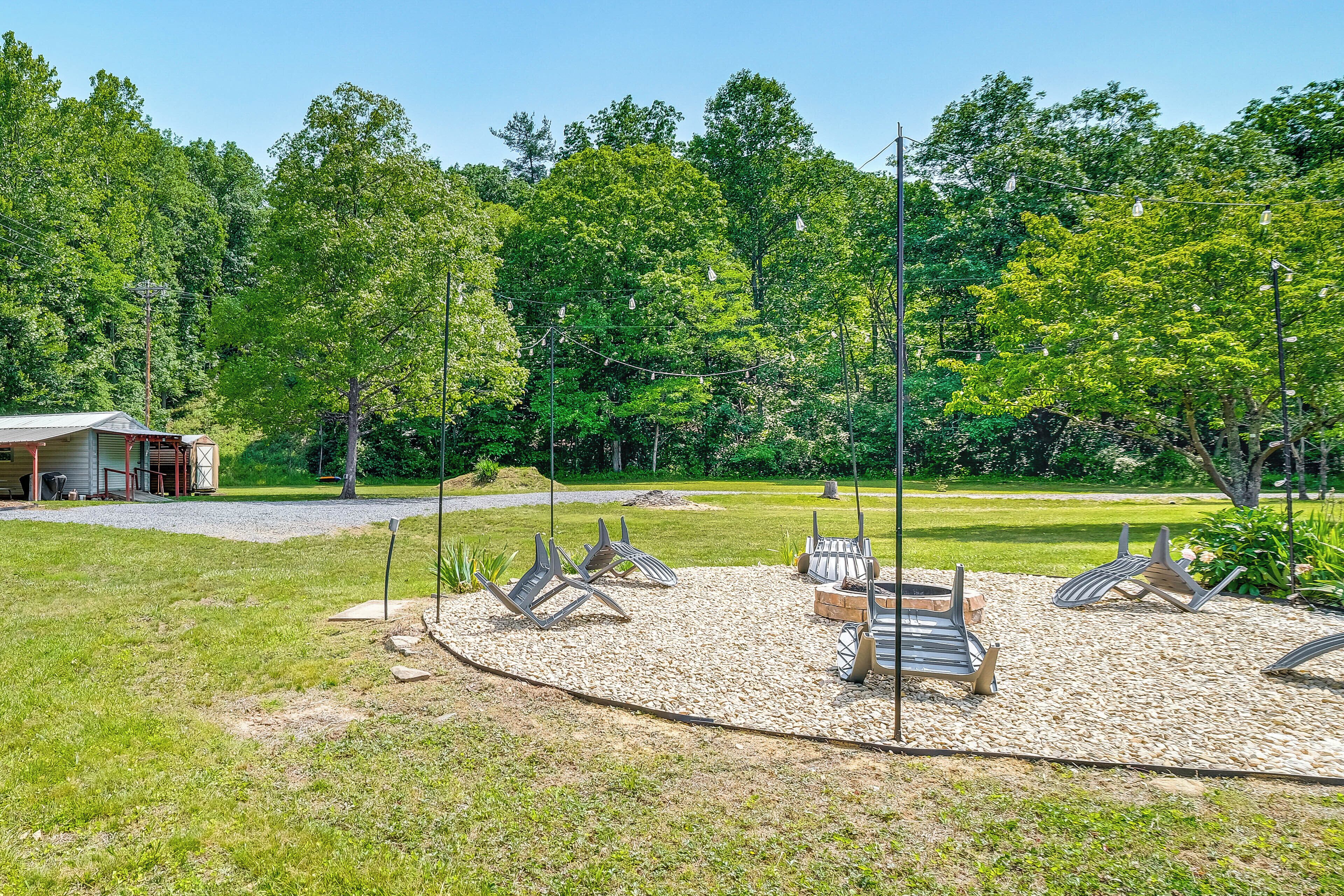 A serene outdoor seating area with multiple chairs and tables, surrounded by a gravel path and lush greenery.