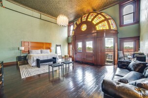 Una habitación amplia con una cama grande, un sofá de cuero y una ventana con vidrieras.