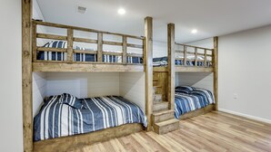 A room with two bunk beds, wooden flooring, and a staircase leading to the upper bunk. - Baldwin Lakefront Home: Dock, Fire Pit & Trails! (Baldwin)
