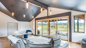 A spacious living area with a gray sofa, a coffee table, and a view of a mountainous landscape through large sliding glass doors. - Salida Ranch Home w/ Mountain Views! (Salida)