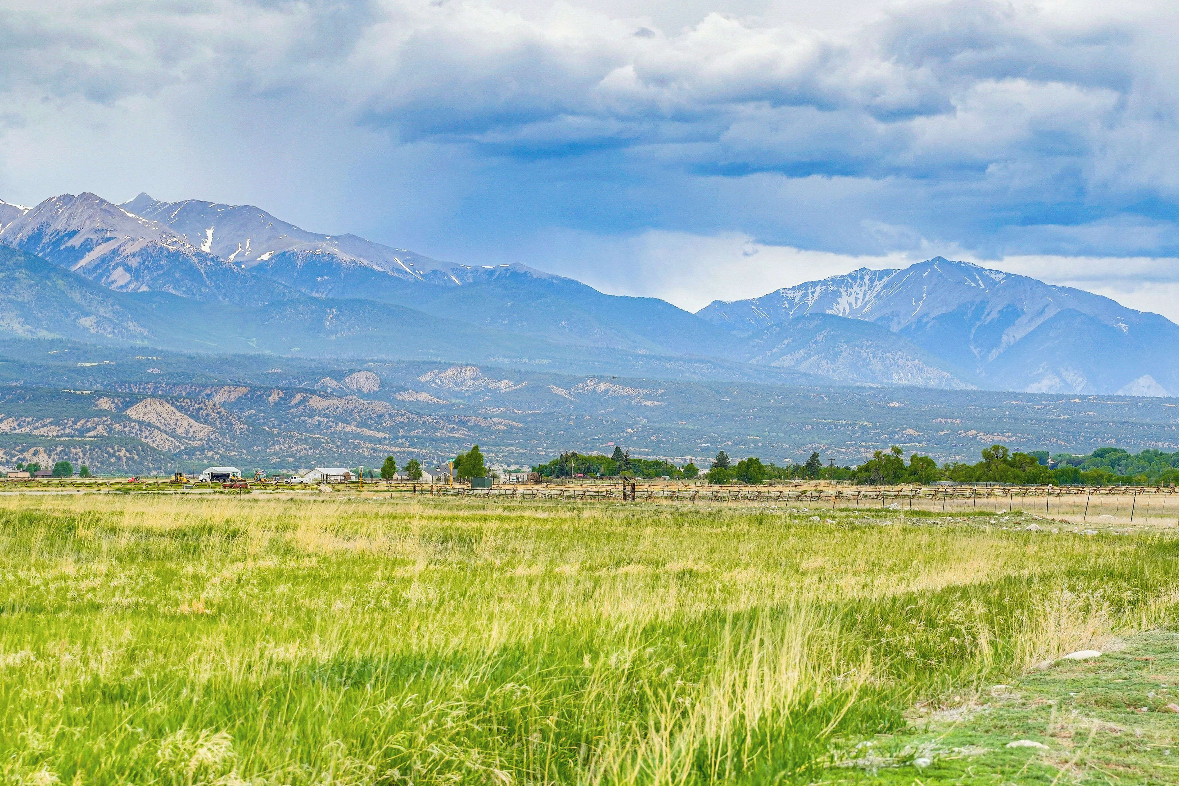 A mountainous landscape with a field in the foreground and a village in the midground.