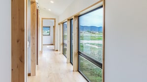 A corridor with large windows and wooden flooring, leading to a room with a view of a landscape. - Salida Ranch Home w/ Mountain Views! (Salida)