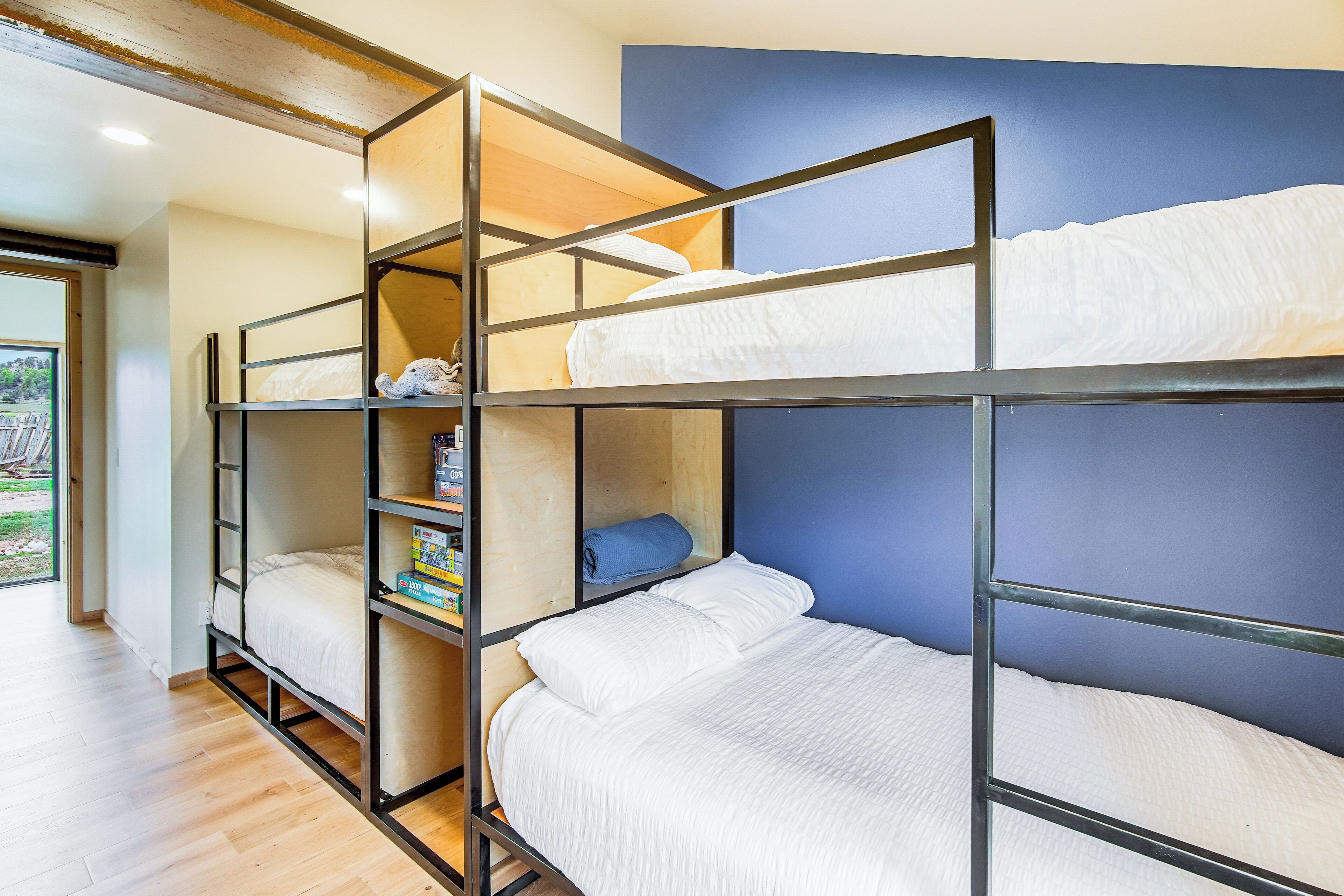 Een slaapkamer met stapelbed, een blauwe wand en houten vloeren.
