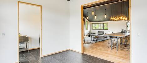 A modern kitchen with wooden accents, a dining area with bar stools, and a view of the outdoors.