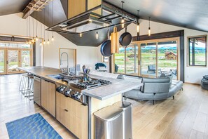Una cucina moderna con isola centrale, elettrodomestici in acciaio inossidabile e un'ampia finestra con vista su un paesaggio suggestivo.