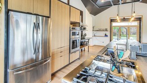 A modern kitchen with stainless steel appliances, wooden cabinets, and a central island with a gas stove. - Salida Ranch Home w/ Mountain Views! (Salida)