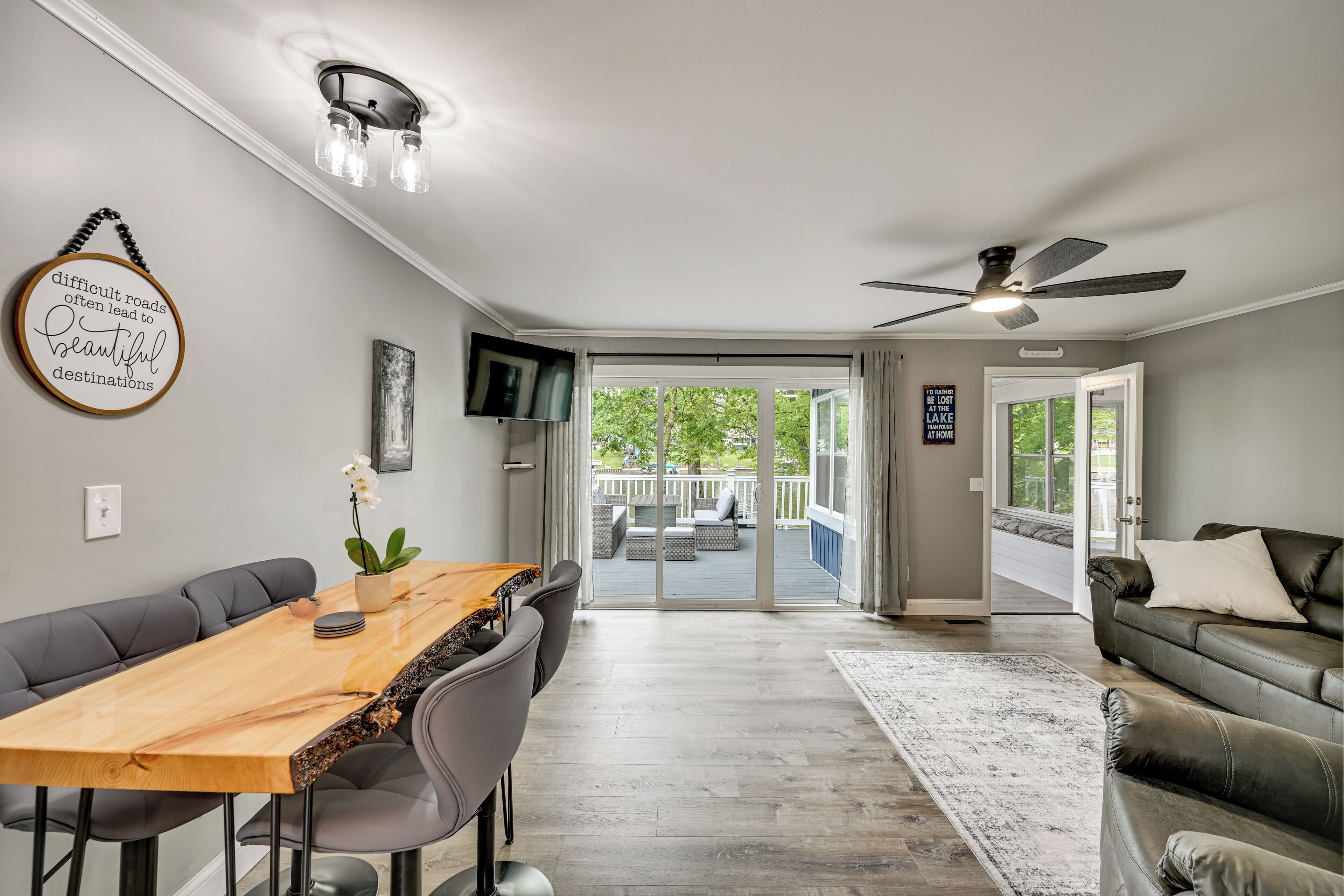 A modern living room with a dining area, a ceiling fan, and a view to the outside.