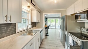 Una cocina moderna con armarios blancos, un refrigerador de acero inoxidable y un horno empotrado.