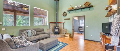 A cozy living room with a fireplace, a sofa, a television, and a wooden floor.