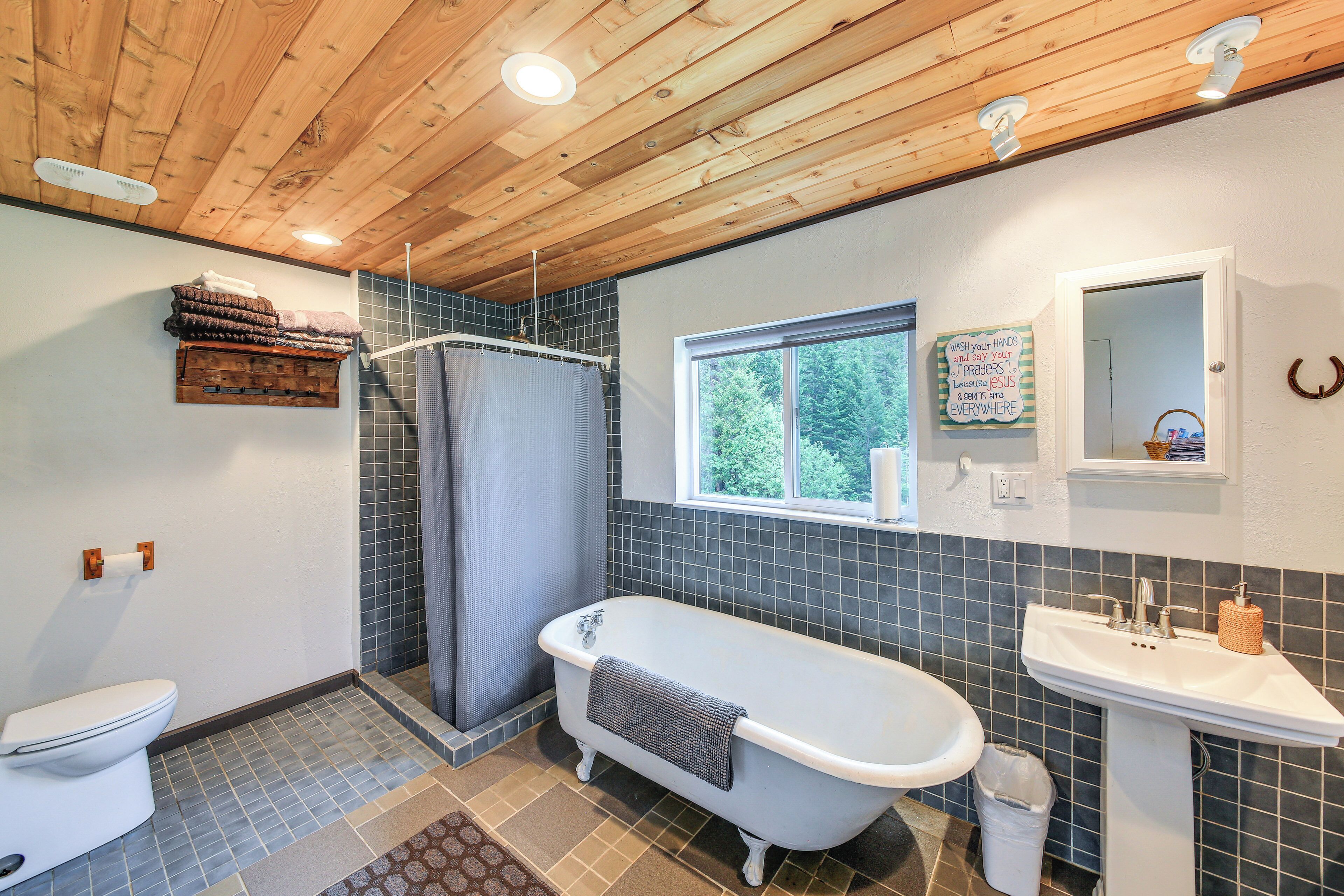 A bathroom with a wooden ceiling, a bathtub, a sink, and a toilet.