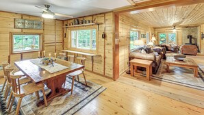 L'intérieur d'un chalet en bois comprend un coin repas, un canapé et une cheminée.