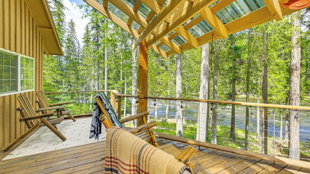 Une terrasse en bois offrant une vue sur une forêt et un plan d’eau.