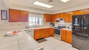 A kitchen with wooden cabinets, a stainless steel refrigerator, a built-in oven, and a window providing natural light.