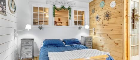 Een slaapkamer met een bed, twee nachtkastjes, een houten wandpaneel en een raam met een bordje met de tekst 'Grateful' erboven.