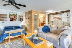 Un salon confortable avec un lit, un canapé, une table basse et une porte en bois donnant sur une autre pièce.