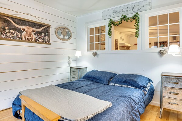 Une chambre à coucher comprenant un lit, une table de chevet, une commode, une fenêtre donnant sur un beau paysage et des éléments de décoration murale.