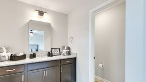 A modern bathroom with dark cabinets, a large mirror, and a countertop with toiletries.