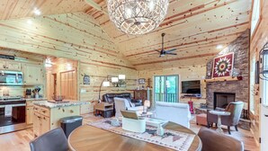 Interior acogedor de una cabaña con comedor, cocina, sala de estar y chimenea.