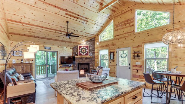Una cabaña de madera espaciosa con una isla grande en la cocina, zona de comedor y una sala de estar acogedora con chimenea.