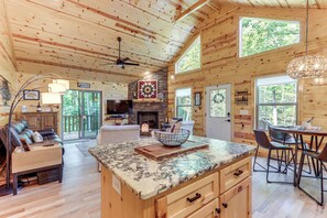 A spacious wooden cabin with a large kitchen island, dining area, and a cozy living room with a fireplace. - 10 Mi to Main St Murphy: Cabin w/ Covered Deck! (Murphy)