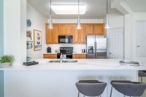 A modern kitchen with wooden cabinets, stainless steel appliances, and pendant lighting. - Close to EPIC and Convention * next to pool (Orlando)