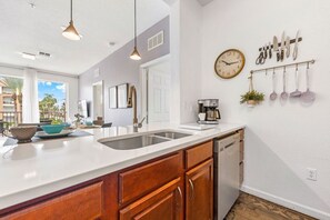 A kitchen with a white countertop, wooden cabinets, a dishwasher, and a wall-mounted knife rack.