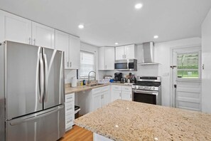 A modern kitchen with white cabinets, stainless steel appliances, granite countertops, and a built-in oven.