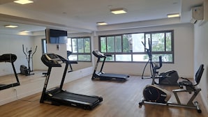 Un gimnasio con cintas de correr, elípticas y una bicicleta estática.